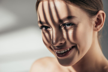 Wall Mural - portrait of smiling girl with shadows on face on grey