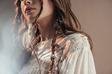 Wall Mural - cropped view of bohemian woman with braids in hairstyle posing in white boho dress on grey with lens