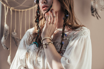 Wall Mural - cropped view of girl with braids in white boho dress on beige with dream catcher