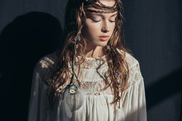 Wall Mural - young tender woman with braids and closed eyes in white boho dress on grey