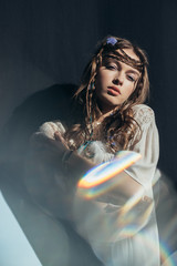 Wall Mural - attractive girl with braids in hairstyle posing in white boho dress on grey with lens flares