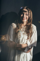 Wall Mural - attractive happy girl with braids in hairstyle posing in white boho dress on grey with lens flares