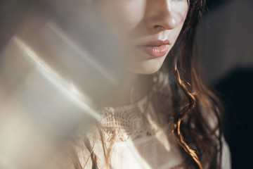 Wall Mural - cropped view of boho girl with braids in hairstyle posing in white dress on grey with lens flares