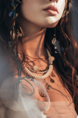 Wall Mural - cropped view of nude boho girl with necklace posing on grey with lens flares