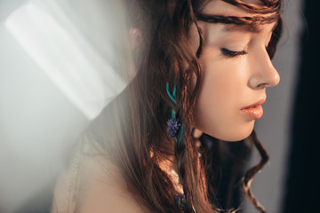 Wall Mural - tender boho girl with braids in hairstyle posing on grey with lens flares