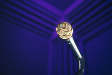 Wall Mural - golden microphone on stand, purple background with acoustic foam in studio