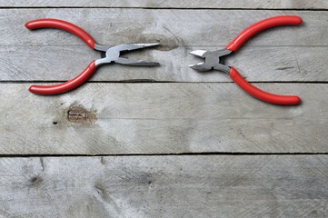 nippers and pliers with red handles on a wooden background. copy space.