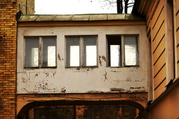 Three old rusty windows in white corridor bridging buildings