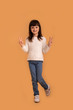 © Marharyta Hanhalo - Picture of little girl child in full length on orange background showing peace gesture with hands. Cute beautiful girl, happy and carefree lifestyle. Vertical image.