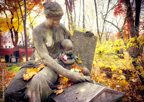 Beautiful funerary monument of a young woman and child with a fresh rose in hand at Alter Nordfriedhof (old cemetery North), dismiss graveyard now public park and green space for jogging and relax