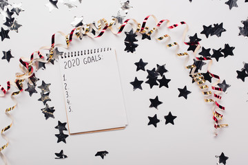 Canvas Print - top view of notebook with 2020 goals list with empty points near decorative, shiny stars and serpentine on white table