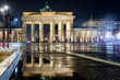 Das Brandenburger Tor in Berlin bei Nacht und Regen im Winter mit Reflektionen im Regenwasser