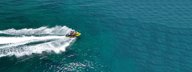Wall Mural - Aerial photo of jet ski with couple cruising in high speed in Caribbean tropical crystal clear waters