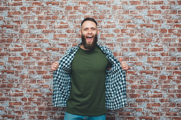 Wall Mural - City portrait of handsome hipster guy with beard wearing a blank green military t-shirt standing on a brick wall background. Empty space for your logo or design. Mockup for print.