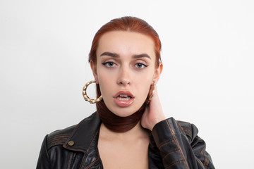 Wall Mural - Sexy redhead girl posing in leather jacket on white background