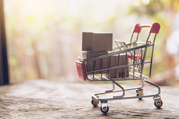 Shopping concept - Cartons or Paper boxes in shopping cart on brown wood table. online shopping consumers can shop from home and delivery service. with copy space.