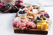 © timolina - Antipasto platter with ham, prosciutto, salami, cheese,  crackers and olives on a light background.  Christmas table.