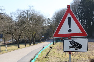 A lonely road in Bavaria with a warning sign at the side telling people about frogs crossing at night