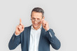 © Viktoriia - Freestyle. Mature businessman in eyeglasses standing isolated on white winking to camera playful