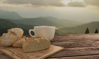 Wall Mural - home made bread and  butcher in breakfast  concept on wooden table. Blur latte art coffee with chocolate sauce and caramel sauce  on Milk foam in white cup. Background mountian view and sunrise. 3D re