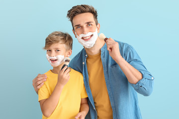 Poster - Father with son applying shaving foam onto their faces against color background