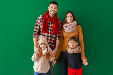 Happy family in winter clothes on color background