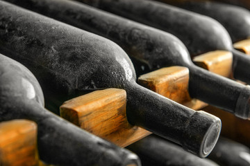 Wooden holder with bottles of wine in cellar, closeup