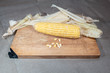 Patch of corn peeled on a wooden board with grains on a fabric background.