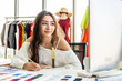 © TeTe Song - Asian woman designer are thinking and drawing something on paper for customers order items at the designer desk in the studio. Clothes designers are working in the office. Startup designer concept.