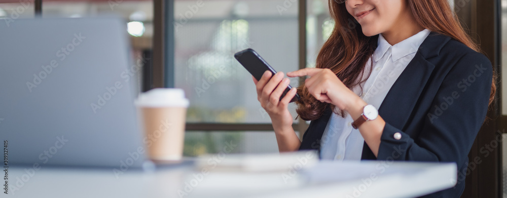 Closeup image of a businesswoman using mobile phone in office - obrazy, fototapety, plakaty 