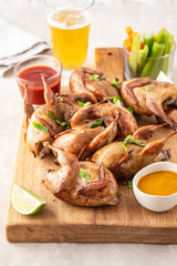 Wall Mural - Baked quail with sauces, lime and beer on a wooden board.