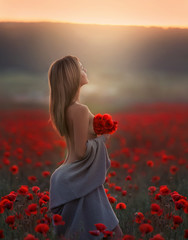 A beautiful woman with bare shoulders and a long sweater in a field with poppies.