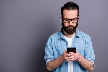 Portrait of concentrated freelancer blogger man use smart phone read social media information chat with clients colleagues wear good look jeans outfit isolated over grey color background
