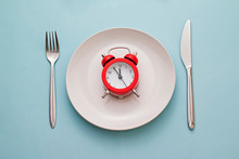 Red Alarm Clock On A Clean White Dinner Plate