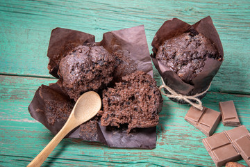 Fresh baked muffins, chocolate slices and a spoon on a wooden green table for the holiday