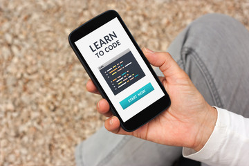 Wall Mural - hand holding smart phone with learn to code concept on screen