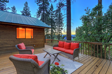 Luxury summer evening mountain home eteriors with cozy porch fire table and new furniture design.