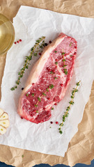 Wall Mural - Big whole piece of raw beef meat, striploin on white parchment paper on craft background, zero waste packing. Seasoning steak with salt