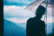 Silhouette of young woman looking at the rain over the mountains.