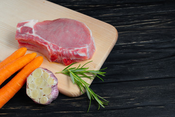 Wall Mural - Top view of one pieces raw pork chop steaks with cherry tomatoes rosemary and garlic on a cutting board.