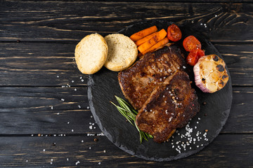 Wall Mural - juicy piece of fried meat lies on a stone plate against a black wooden table