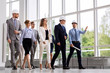 © Syda Productions - architecture, construction business and building concept - happy group of architects in helmets with blueprint walking along office building