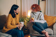 © cherryandbees - woman friends sitting sofa at home talking