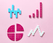 © Yaroslav Danylchenko/Stocksy - Colored plastic construction block pattern on a pink background.