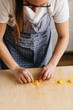 © Laura Stolfi/Stocksy - Young woman shaping fresh ravioli on wooden cutting board