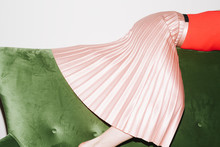 Woman With Pink Pleated Skirt On Green Velvet Couch