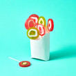 © Yaroslav Danylchenko/Stocksy - White cardboard box with colorful lollipops on a blue background with space for text