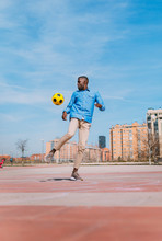 Black Man Playing With A Yellow Soccer Ball Outdoors
