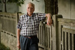 © guille Faingold/Stocksy - Elderly man in plaid shirt leaning on fence