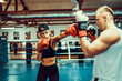 © zamuruev - Young woman exercising with trainer at boxing and self defense lesson.